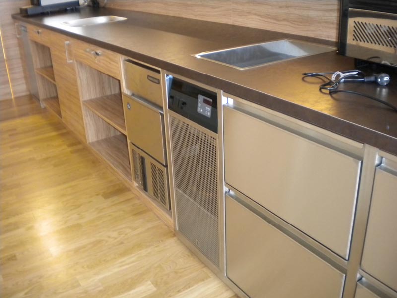 Die Barzeile kombiniert Tischlerarbeit und CNS Einbau Module. Steckerfertiges Kühlpult mit Aggregat und Eiswürfelbereiter. Flaschenkühlwanne flächenbündig in Holzoberplatte eingebaut mit CNS-Rahmen